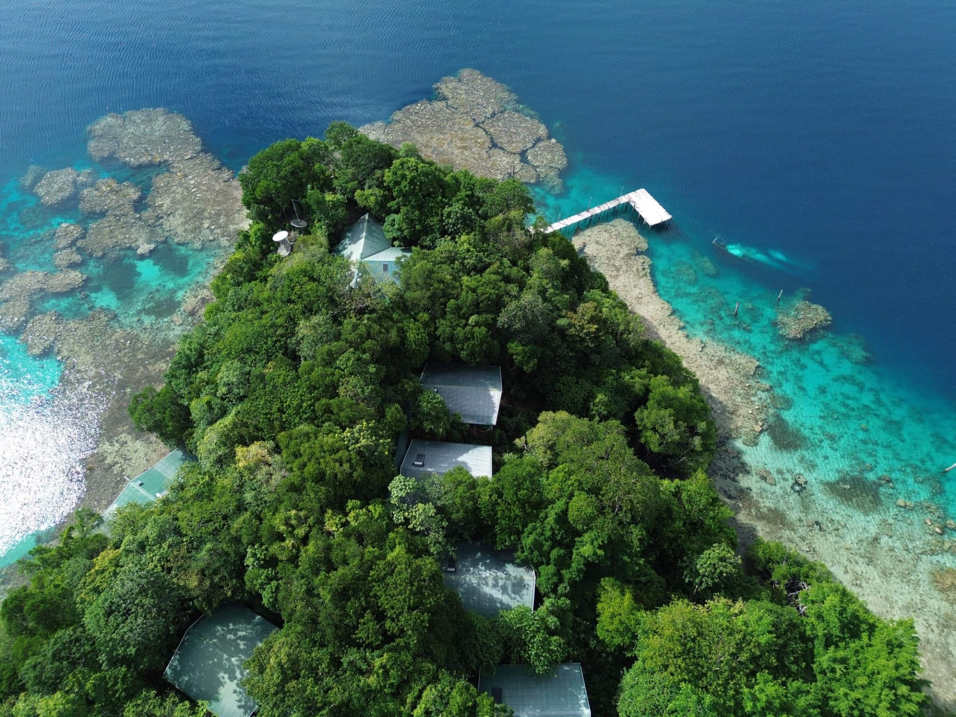 Aerial view of Tawali Resort bungalows above the coral reef at sunrise